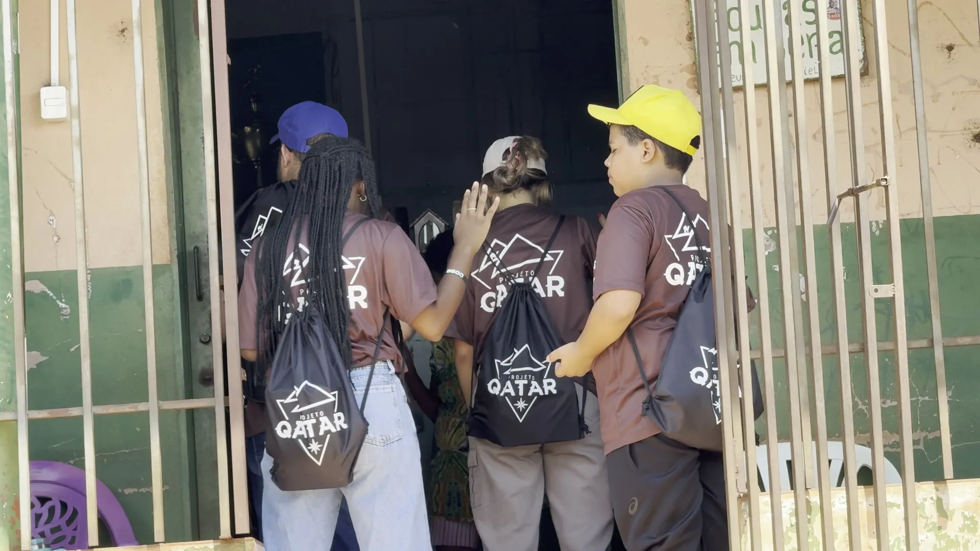 Equipe do Projeto Qatar conversando com moradores no portão, em Delta